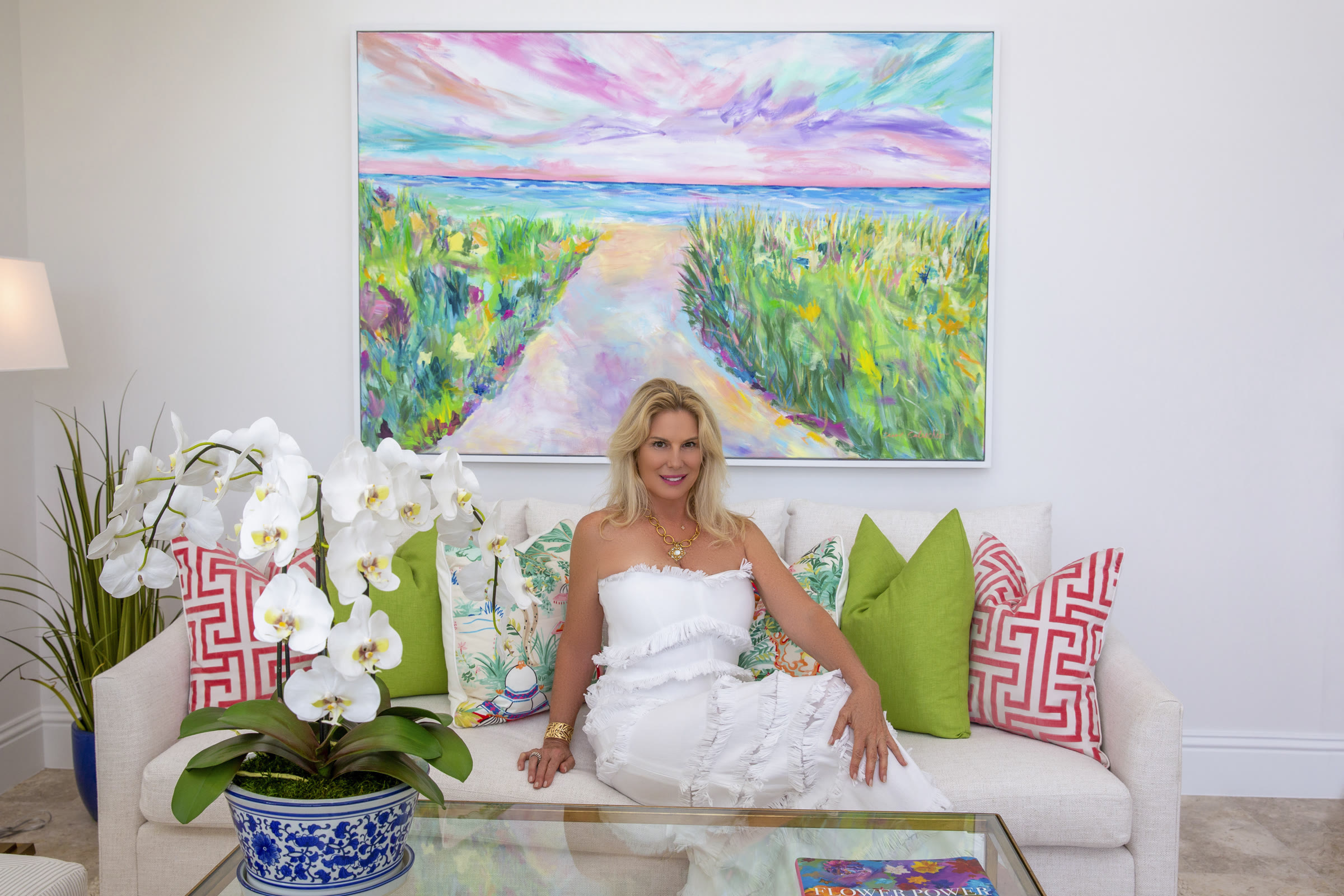 Carol Calicchio seated beneath one of her landscape paintings in a collector's living room